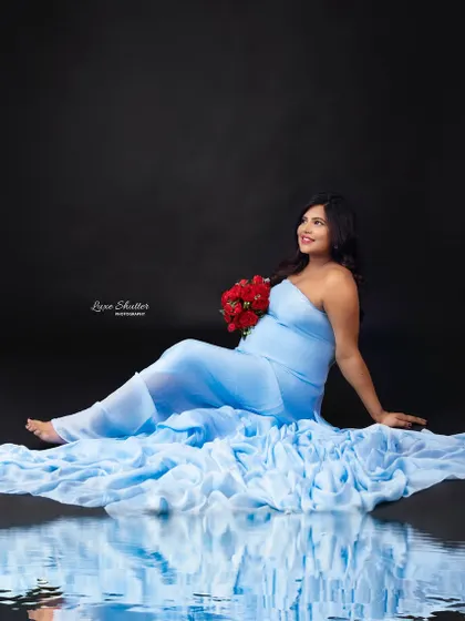 A serene and dreamy portrait. The mother-to-be looks like a water goddess in this light blue gown, with the reflection adding a beautiful, artistic touch.
