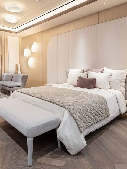 A minimalist bedroom in a Gurgaon apartment, designed for simplicity and flow. The space features a custom bed with a light wood frame and a matching bench, set against a paneled wall. The design creates a soft, serene atmosphere that feels both elevated and deeply restful.