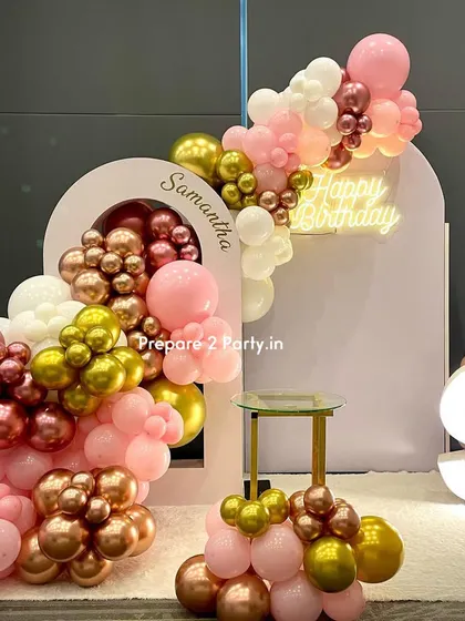 A premium birthday backdrop with a unique double-arch design. A cascade of pink, white, and metallic balloons flows through the arches, creating a modern and dynamic photo wall.