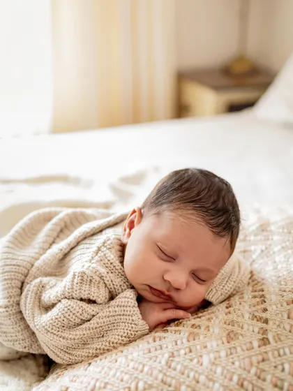 A newborn sleeping peacefully on a comfy bed. Lifestyle sessions are perfect for capturing these serene moments in a natural, unposed way.