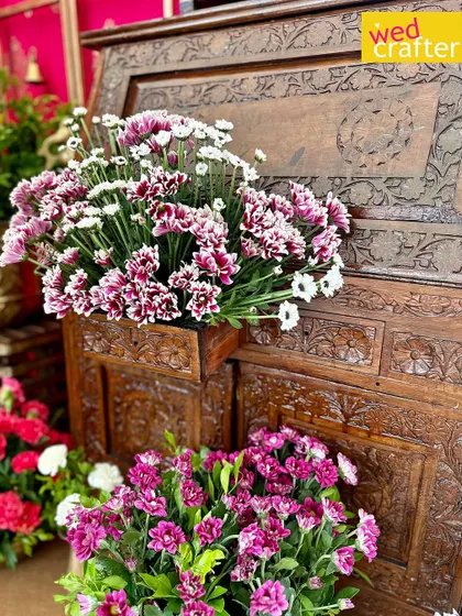 Beautiful purple and white chrysanthemums arranged against a backdrop of an intricately carved antique wooden chest.