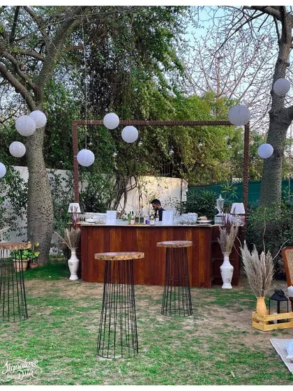This outdoor event featured a full-service wooden bar set under a simple frame, allowing the natural beauty of the garden to shine. White paper lanterns and pampas grass arrangements tied the look together.