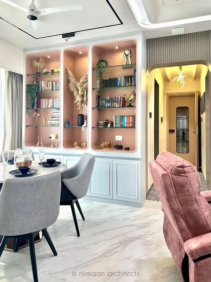 This dining area is defined by a custom bookshelf with a soft pink interior. It adds a pop of color and provides a beautiful backdrop for displaying books and artifacts, making the space feel personal and curated.