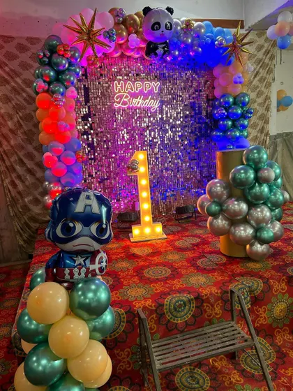 A close-up of the mixed-theme first birthday backdrop, featuring a Captain America balloon and a light-up number '1'.