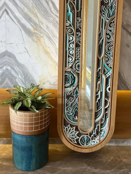 A unique two-toned ceramic planter adding an artistic touch next to an intricately designed mirror. We source unique pieces that act as decor in their own right.