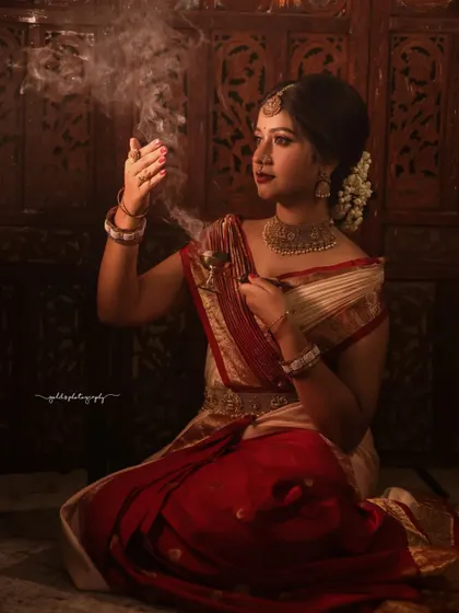Portraits from a makeup shoot, showcasing a model in a classic red and cream saree. The images highlight the flawless makeup and traditional styling in a beautiful garden setting.