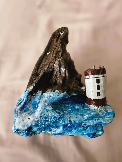 A work-in-progress shot of a driftwood piece. Here, a tiny lighthouse sits on a sculpted wave, waiting for its final details. This is the blank canvas stage of our creative process.