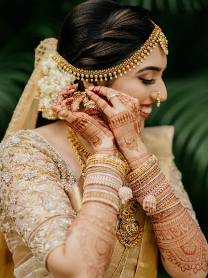 A close-up of our NRI bride Adithi, showing the delicate embroidery on her all-gold blouse and her intricate henna design.