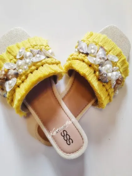 A heart-shaped layout of the yellow macrame slippers. I love how the seashells and pearls add a touch of elegance to the boho design.