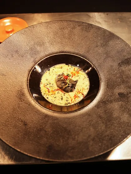 A modern take on a classic Indian dish, served in a contemporary black bowl. The contrasting colours and textures of the morel mushroom and creamy sauce make for a visually stunning presentation.