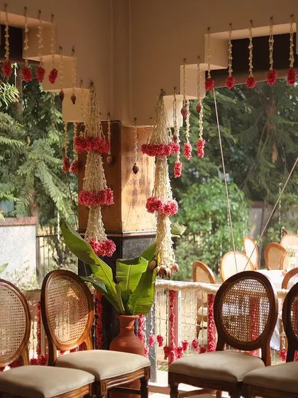 A beautiful composition of hanging floral chandeliers made from jasmine and pink flowers, with elegant cane-backed chairs in the background.