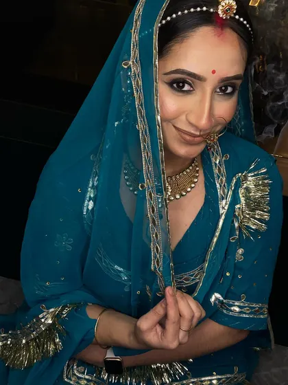 A beautiful still shot of a student's work on a Rajasthani bridal look, capturing the essence of royalty with a teal blue odhani and traditional nose ring.