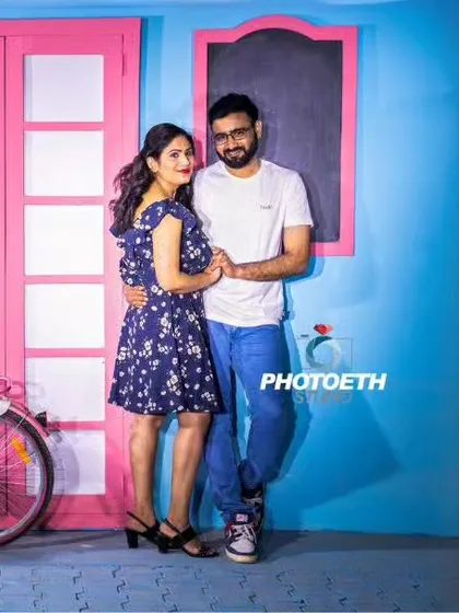 A casual and colorful pre-wedding portrait against a vibrant studio backdrop. The pink bicycle adds a charming, rustic element to the scene.