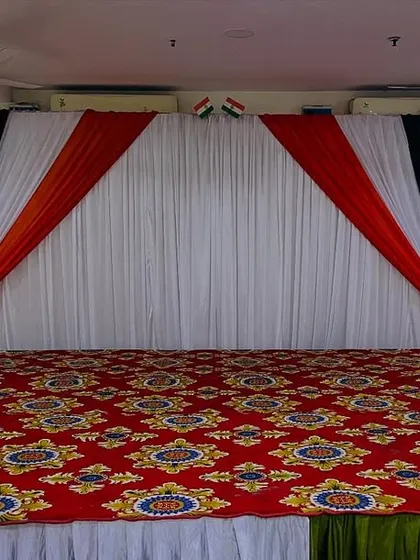 A direct front view of the stage with a red patterned carpet and a saffron, white, and green backdrop, perfect for corporate functions on national holidays.