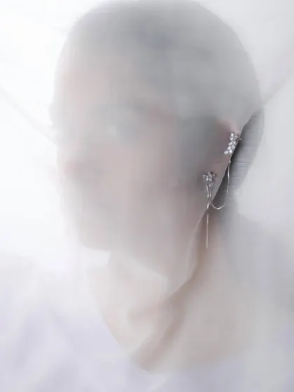 A profile shot of the veiled model, highlighting the elegant line of the jewellery along the ear.