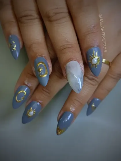 A celestial-themed set with a dusty blue base, adorned with hand-painted gold suns, moons, and stars, plus a white marble accent nail.