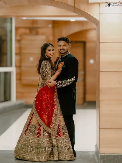 A beautiful portrait of the couple ready for their reception. The bride's stunning red and gold lehenga complements the groom's elegant green sherwani, creating a regal and stylish look.