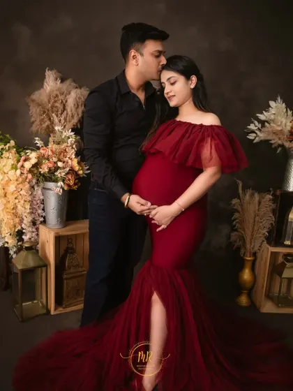 A romantic couple's maternity portrait. The rich red gown stands out beautifully against the moody background, creating a striking and passionate image.