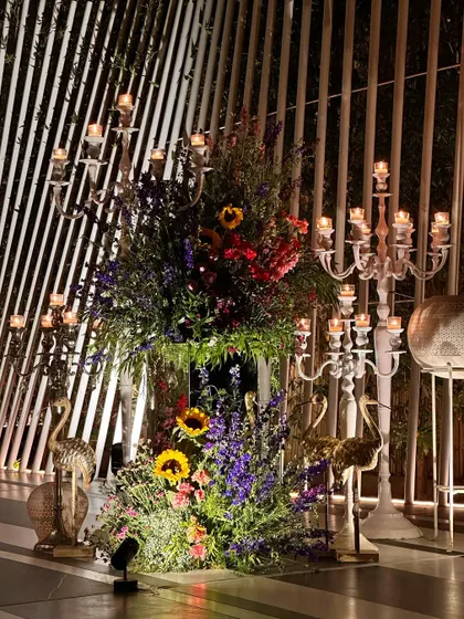A magnificent floral installation with candelabras and golden flamingo accents, creating a dramatic and colorful statement piece.