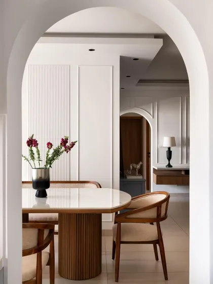 A beautiful arched view into the dining room, highlighting the elegant fluted dining table and classic wall molding. This architectural element was added to create a sense of grace and separation between the living and dining areas.