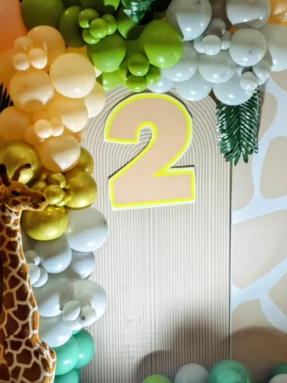 Detail of the balloon arch and backdrop for Arjun's 2nd birthday, showing a large number '2' and a plush giraffe prop.