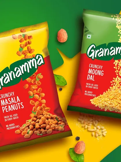 A colorful flat lay for Granamma's Masala Peanuts and Moong Dal. The composition uses scattered ingredients and bold backgrounds to create a visually exciting image for the snack packaging.
