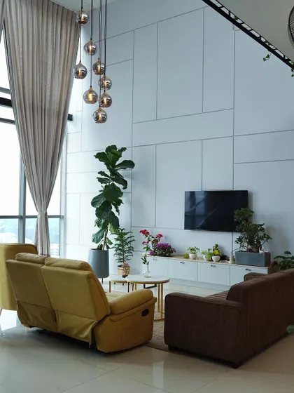 The full view of this double-height living room highlights the floor-to-ceiling windows and sheer curtains that flood the space with natural light, creating a bright and airy atmosphere.