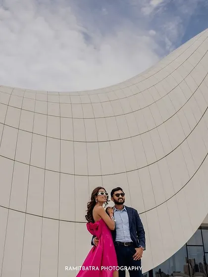 The couple stands together, framed by the sweeping white curves of the Heydar Aliyev Centre.