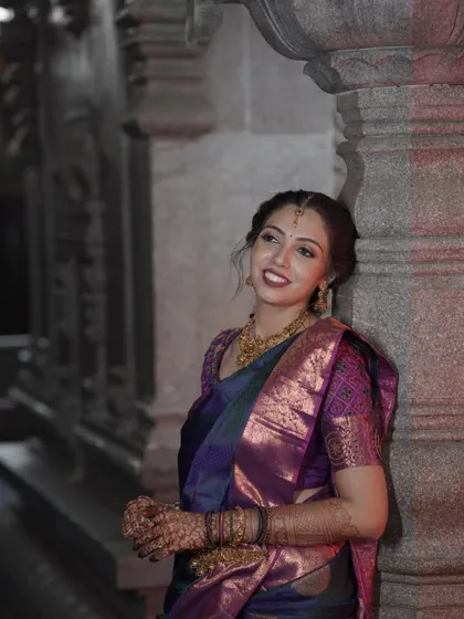 An effortlessly elegant South Indian bridal look. The makeup is soft and romantic, with a beautiful lip color that complements her purple and blue saree.