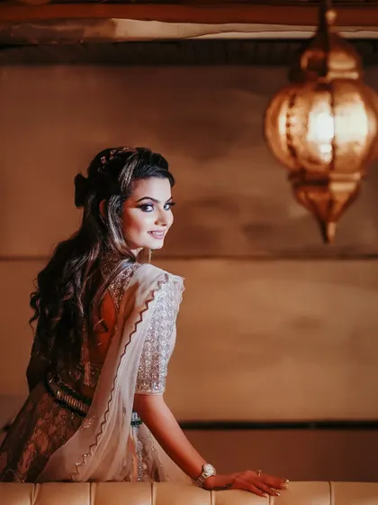 A beautiful solo portrait of the bride, looking over her shoulder with a smile. The warm, ambient lighting from the Moroccan-style lanterns creates a romantic and intimate mood.