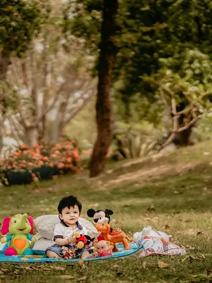 An outdoor portrait of a baby boy enjoying a picnic on the grass with his favorite toys. Including familiar items like stuffed animals can help a child feel comfortable and allows me to capture their natural, happy expressions.