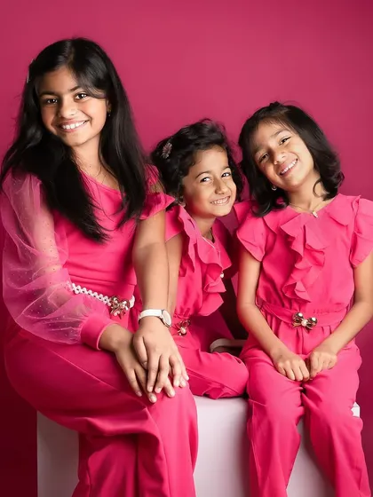 A lovely portrait of three sisters. Their bright pink outfits and happy smiles create a photo that is full of life and personality.