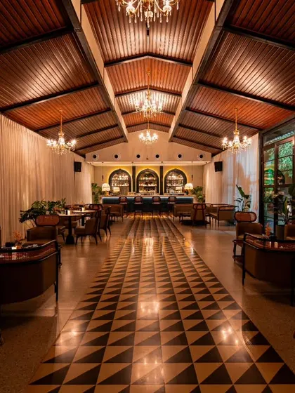 A long shot down the main hall of Vamos Experience at night. This photograph captures the moody, sophisticated atmosphere created by the chandeliers and accent lighting, showcasing the venue's transformation from day to night.