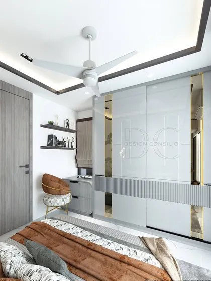 This view of the bedroom showcases the modern sliding wardrobe with glossy white and gold-accented panels. A compact study nook is neatly tucked into the corner, making the room multi-functional.