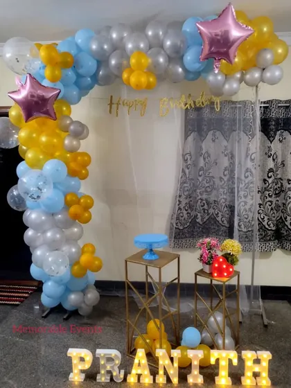 Another midnight surprise setup with a pastel blue and yellow balloon arch, star-shaped foil balloons, and marquee letters.