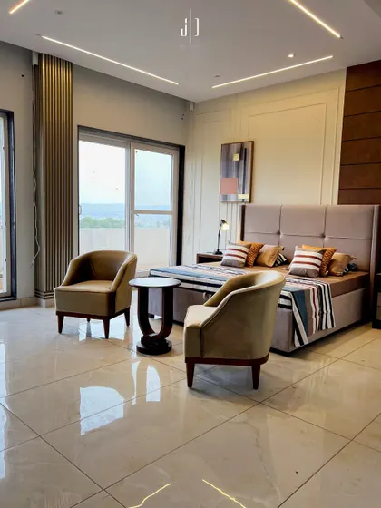 This spacious bedroom is designed with large windows to maximize natural light and views. The neutral-toned furniture and minimalist decor create a calm and uncluttered environment.