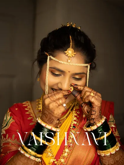 A stunning close-up of the bride, Vaishnavi, as she adjusts her traditional Maharashtrian nose ring (nath).