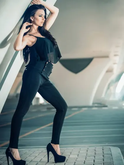 A full-body shot using the strong lines of modern architecture to frame the model. The play of light and shadow adds depth to this chic, all-black ensemble.