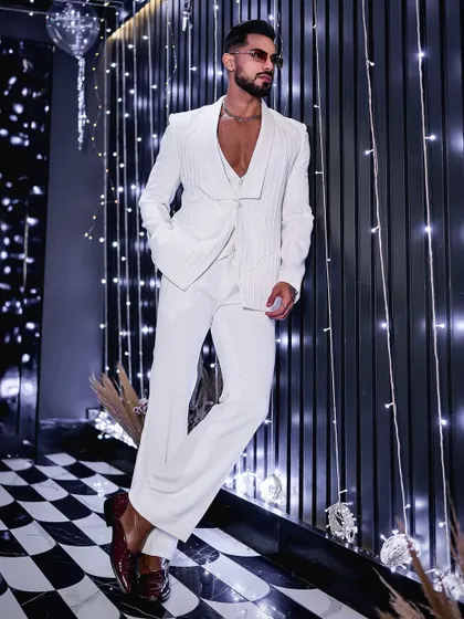 The textured white suit jacket, styled against a dramatic backdrop. The pleating detail on the fabric adds a unique dimension to this standout ensemble, perfect for a fashion-conscious client.