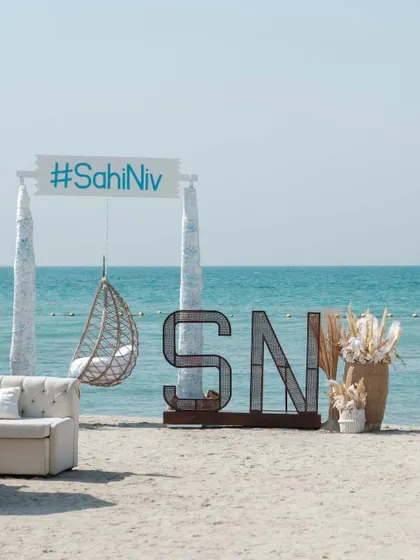A chic beachside setup with a custom sign featuring the couple's wedding hashtag. This creates a perfect, branded photo opportunity for guests.