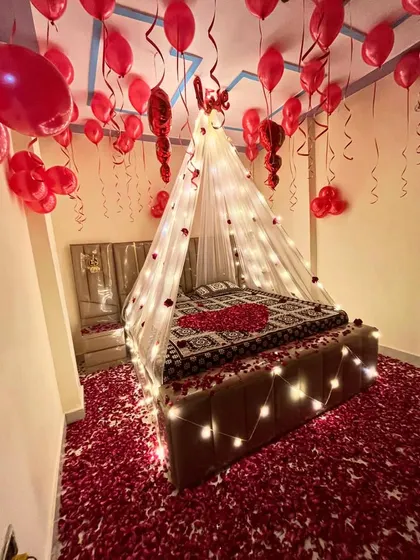 I create truly romantic and memorable experiences. This bedroom decoration features a beautiful canopy with fairy lights, hundreds of red balloons, and a floor covered in rose petals for the perfect surprise.
