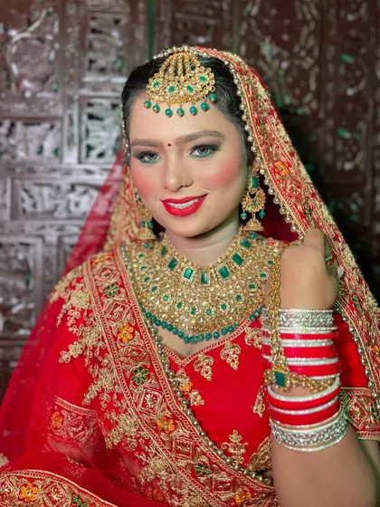 A close-up of the radiant bride. Notice the flawless skin, the perfectly blended eyeshadow, and the bright red lip that ties the entire traditional bridal look together.