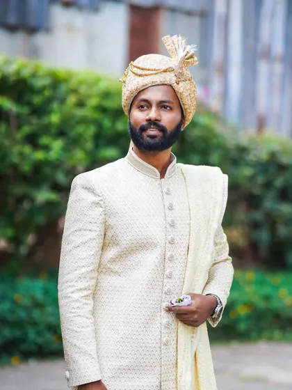A portrait of the groom in a classic cream sherwani and golden pheta, ready for the main wedding ceremony.