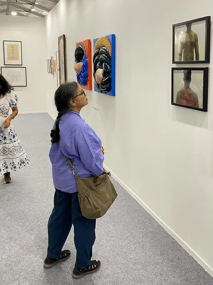 A visitor contemplating the works of G. Ravinder Reddy and Sandeep T K.