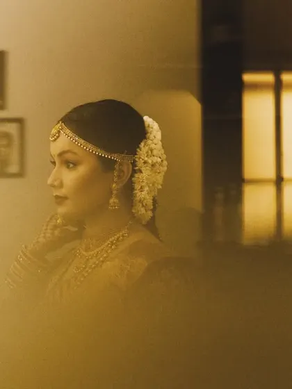 A beautifully framed bridal portrait, with a soft, golden haze creating a dreamy effect. The bride looks away thoughtfully, a picture of grace and elegance.