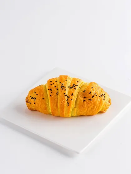 A single, perfect croissant on a clean white plate. This minimalist, e-commerce style shot is all about the product, highlighting its flaky layers and golden color without any distractions.
