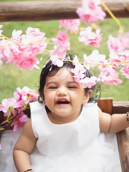 A close-up of the birthday girl, surrounded by pink blossoms. The natural light of an outdoor setting is so flattering and beautiful.