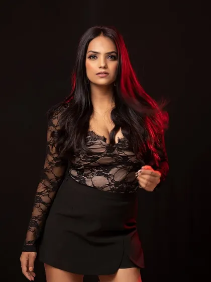 A powerful and direct portrait against a dark background. The red rim light adds a touch of drama, while the lace top adds texture and detail.
