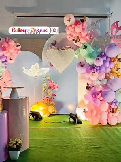 A whimsical butterfly garden theme featuring pastel balloon clouds, large butterfly cutouts, and soft lighting to create a dreamy atmosphere.