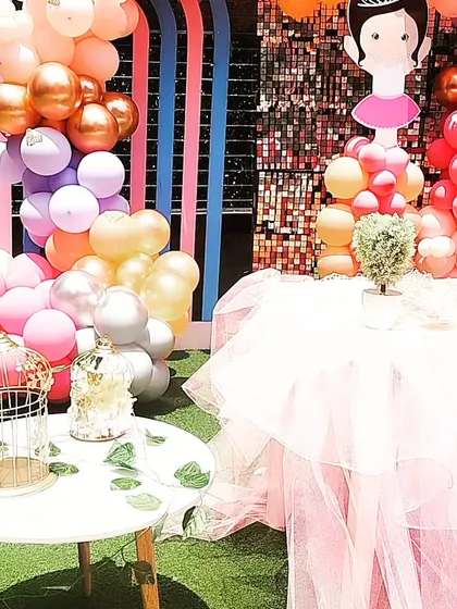 Details of the Ballerina party decor, including a birdcage prop and a table with a tulle skirt, all surrounded by colorful balloons.